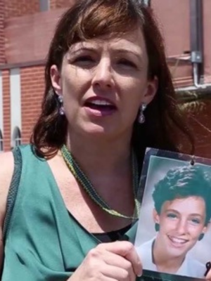 Joelle Casteix holds a photo of herself as a child while speaking at a SNAP event